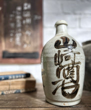 Load image into Gallery viewer, An early 20th Century, Vintage, stone Japanese Saki bottle with calligraphy in brown on cream.