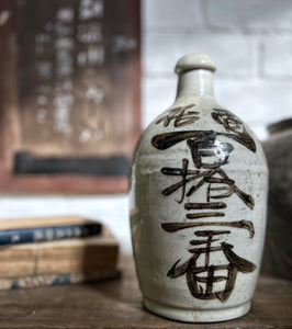 An early 20th Century, Vintage, stone Japanese Saki bottle with calligraphy in brown on cream.