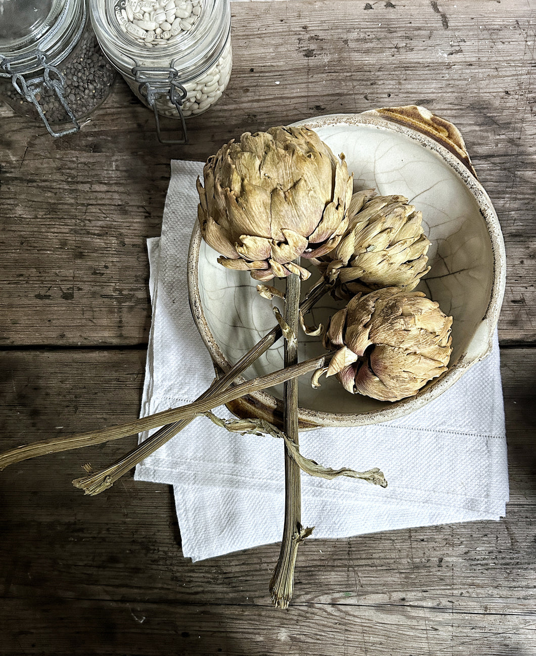 A set of three dried artichoke heads on stems