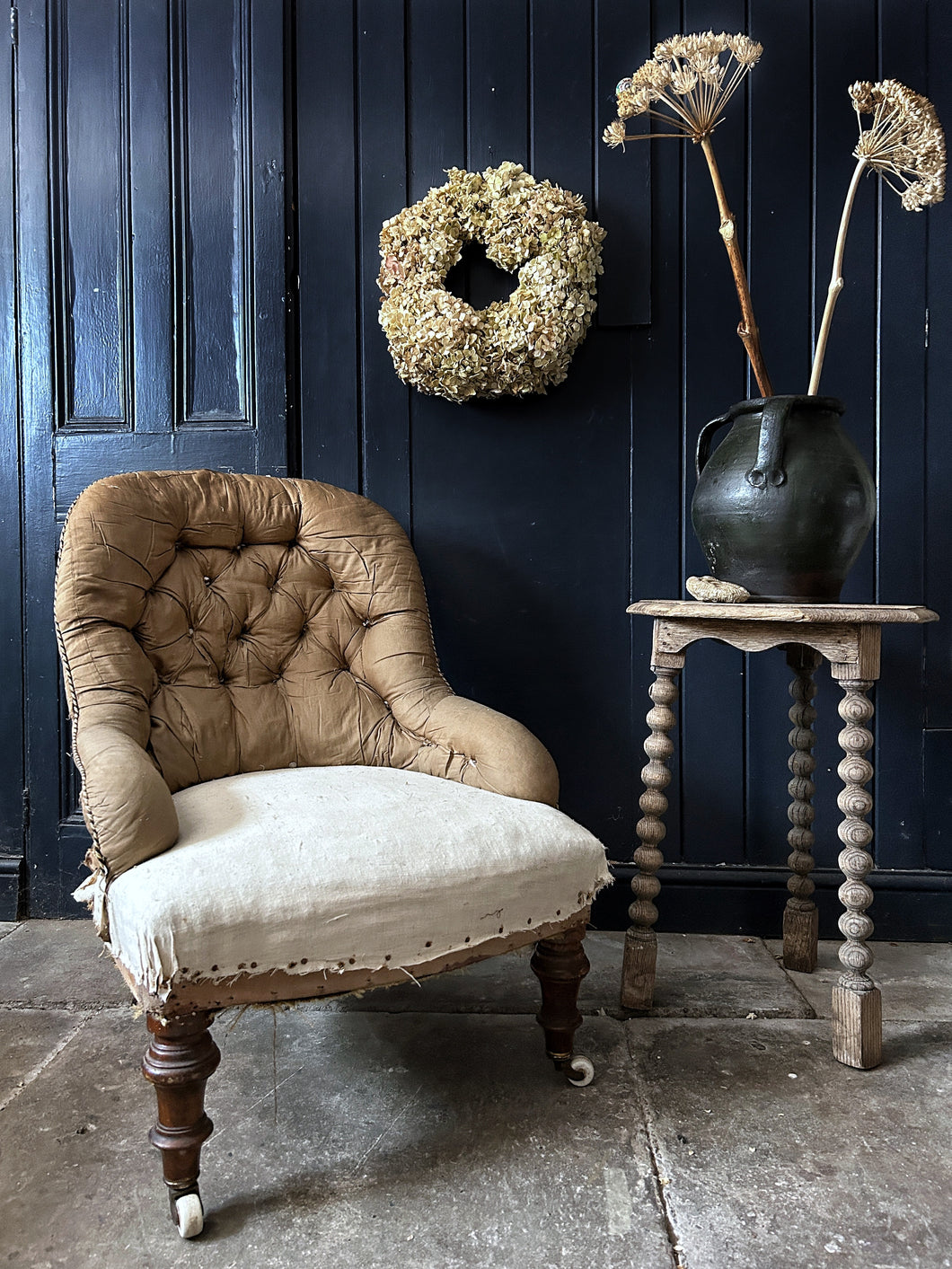 An antique distressed de-constructed button back slipper chair with turned legs & castors