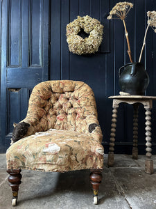 An antique distressed button back slipper chair with original floral linen upholstery & turned legs