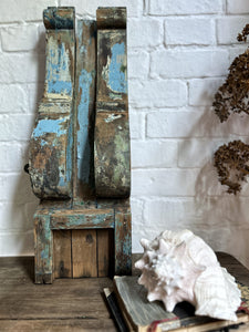 A large wooden scroll shaped bracket with original blue chippy paint