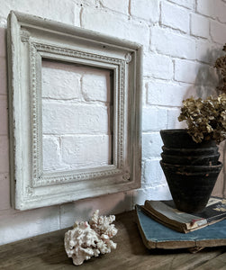 A deep sided white chippy painted decorative wooden vintage picture frame