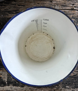 A large vintage enamel measuring jug with measurements inside