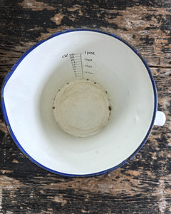 A large vintage enamel measuring jug with measurements inside