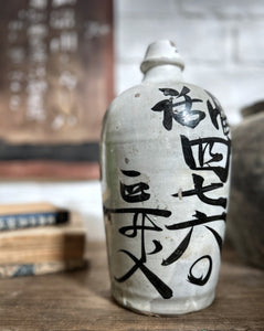 An early 20th Century antique stone Japanese Saki bottle with black calligraphy