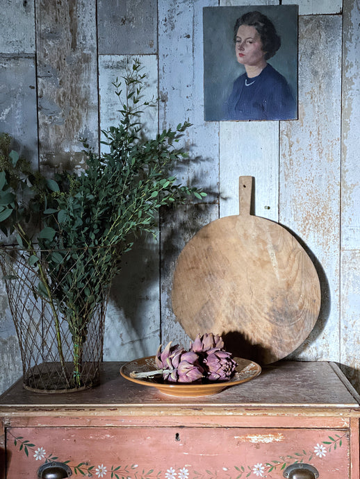 A vintage circular round rustic European hand carved bread serving board